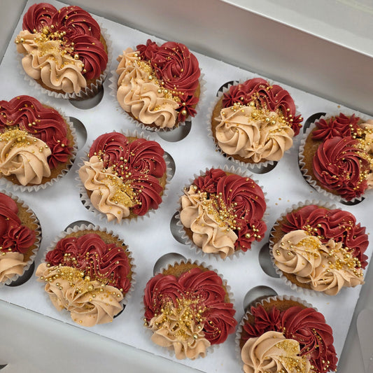 Decorative cupcakes with red, gold, and beige frosting on a tray.