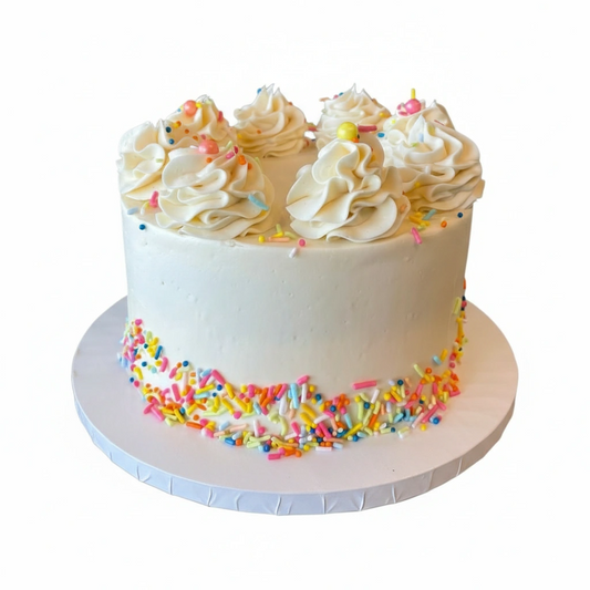 White cake with white frosting, colorful sprinkles, and small yellow candies on a white background